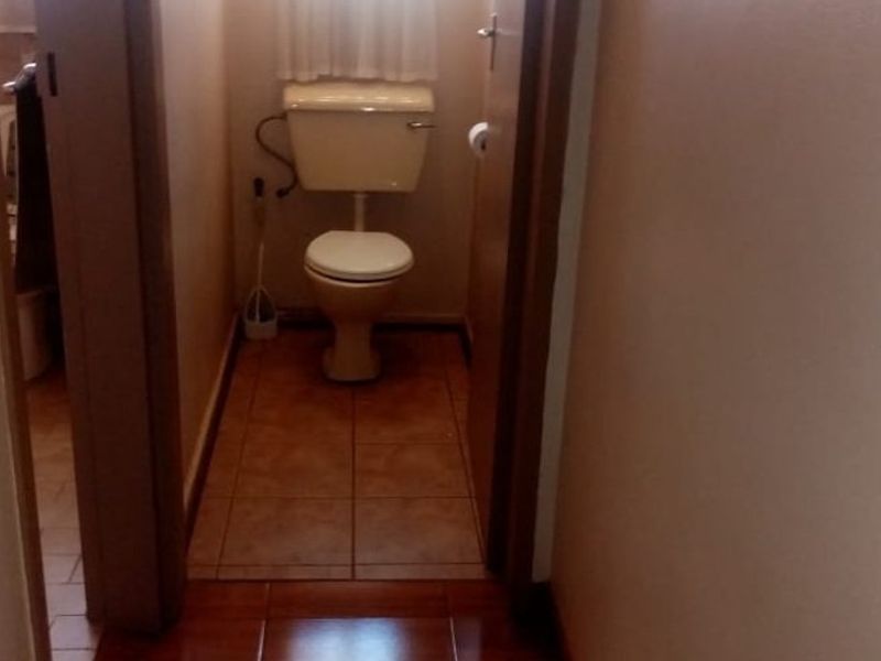 A small, functional separate toilet room featuring ceramic floor tiles and a standard white toilet suite.