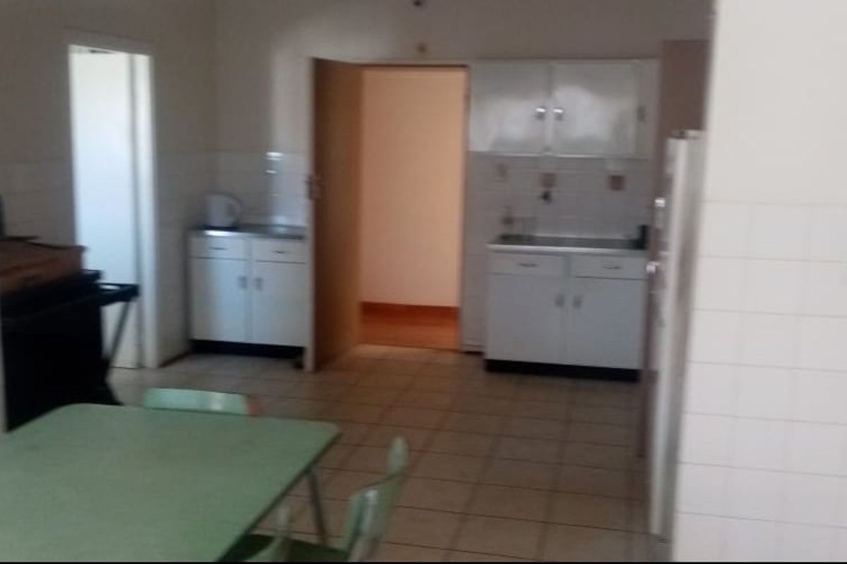 A dated kitchen area featuring built-in cabinetry, tiled splashbacks, and tiled flooring, offering potential for modernization and renovation.