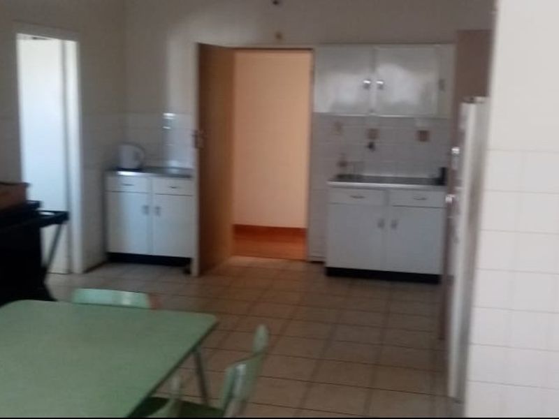 A dated kitchen area featuring built-in cabinetry, tiled splashbacks, and tiled flooring, offering potential for modernization and renovation.