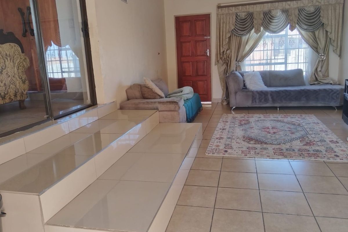 Spacious living area featuring tiled flooring, a raised platform, and direct access to the exterior through a sliding glass door.