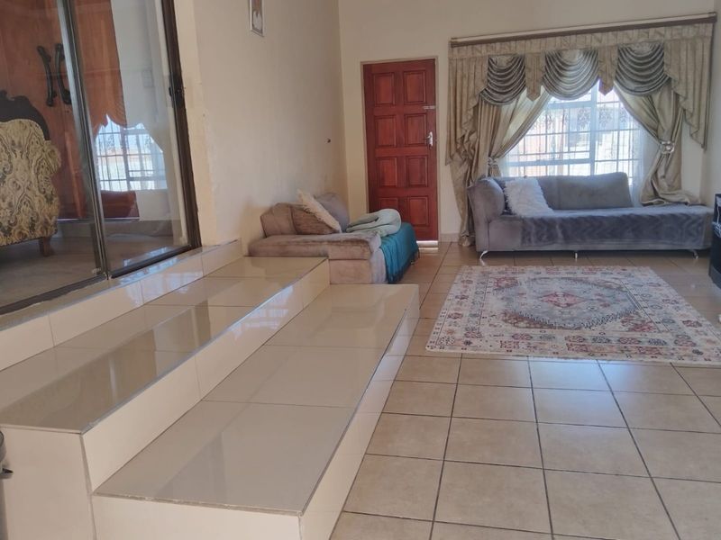 Spacious living area featuring tiled flooring, a raised platform, and direct access to the exterior through a sliding glass door.