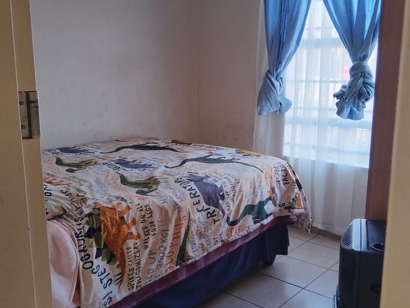 A compact bedroom featuring tiled flooring and a window with curtains, offering a functional space ready for a refresh.