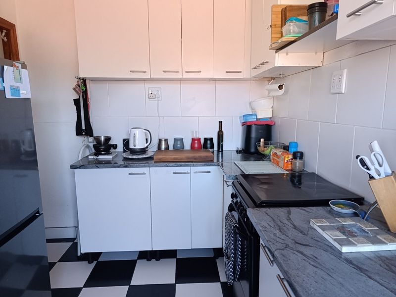 A compact kitchen featuring white cabinetry, stone countertops, a tiled backsplash, and a built-in electric stove with oven.