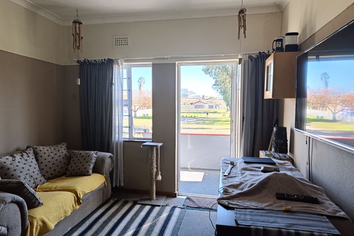 A living room featuring a sliding door leading to an outdoor area, with neutral wall finishes and standard window fixtures.