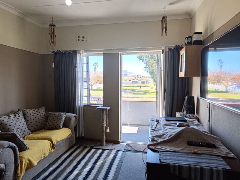 A living room featuring a sliding door leading to an outdoor area, with neutral wall finishes and standard window fixtures.