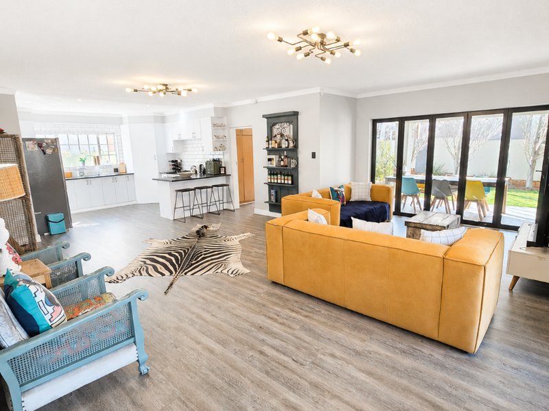 Spacious open-plan living area featuring a modern kitchen with island, laminate flooring, and large bi-fold doors opening to the outdoor patio.