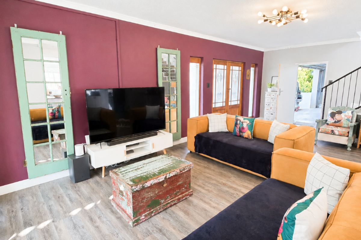 Spacious living room featuring laminate flooring, a bold accent wall, and direct access to adjacent areas through classic french doors.