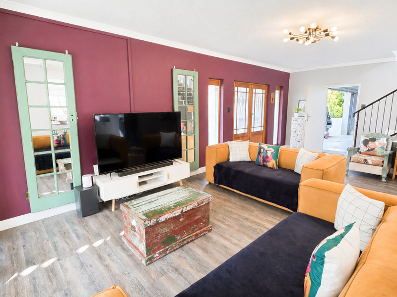 Spacious living room featuring laminate flooring, a bold accent wall, and direct access to adjacent areas through classic french doors.
