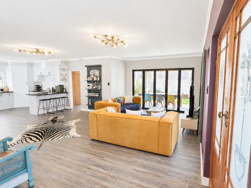 Spacious open-plan living area featuring a modern kitchen with island, laminate flooring, and large bi-fold doors opening to the outdoor space.