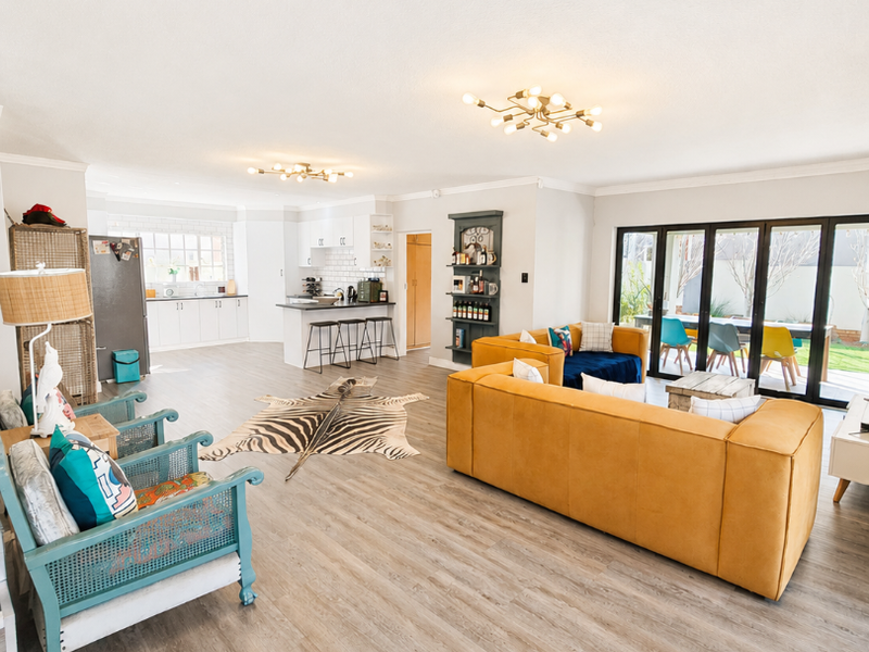 Spacious open-plan living area featuring a modern kitchen with island, light laminate flooring, and large bi-fold doors opening to the outdoor space.