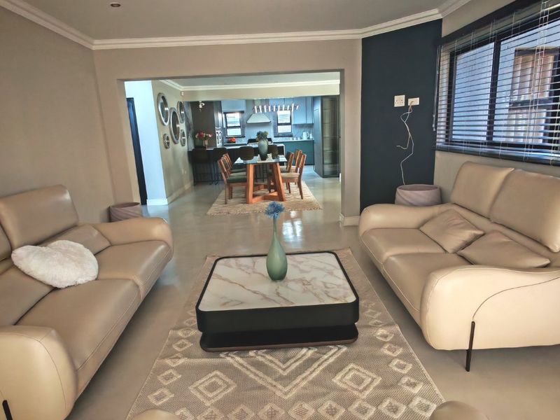 Spacious open-plan living and dining area featuring neutral tones, recessed lighting, and a seamless transition into a modern kitchen space.