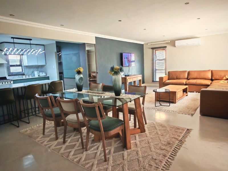 Spacious open-plan living and dining area featuring polished concrete floors, modern kitchen with island, and integrated air conditioning.