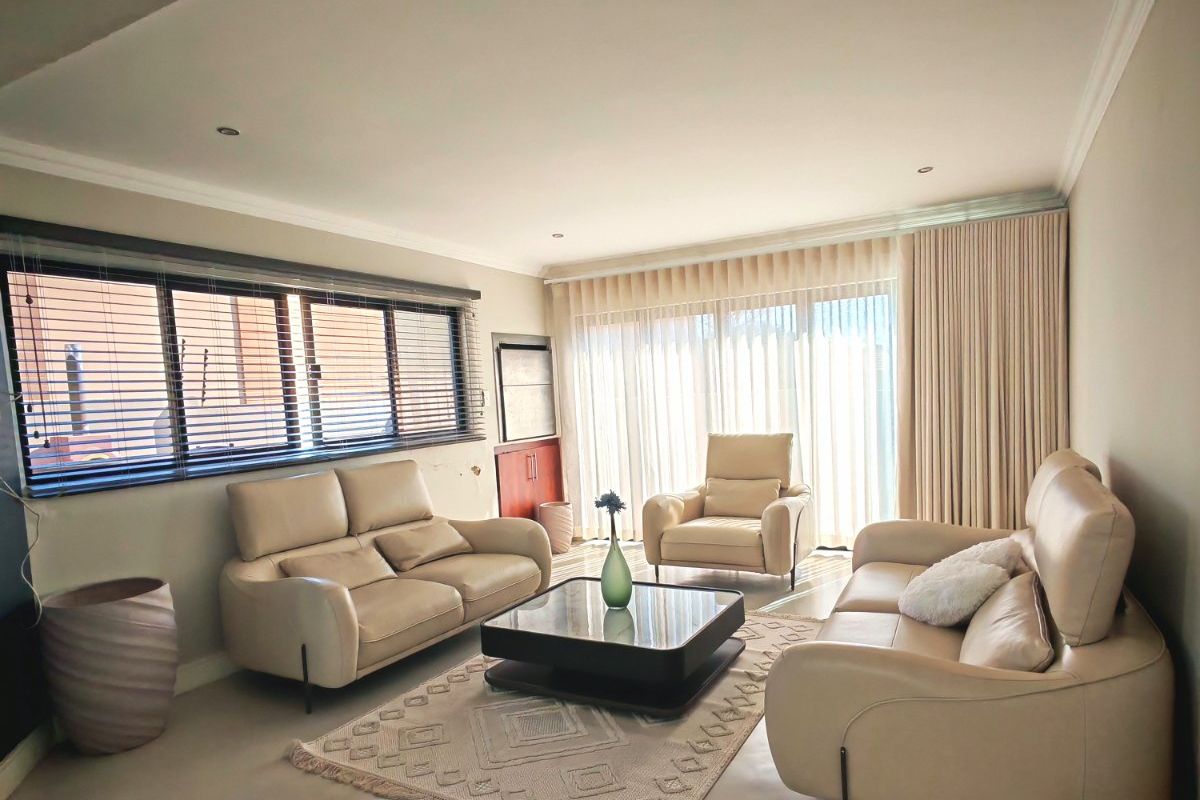 A well-maintained living room featuring polished concrete floors, recessed lighting, and large sliding glass doors that provide ample natural light.