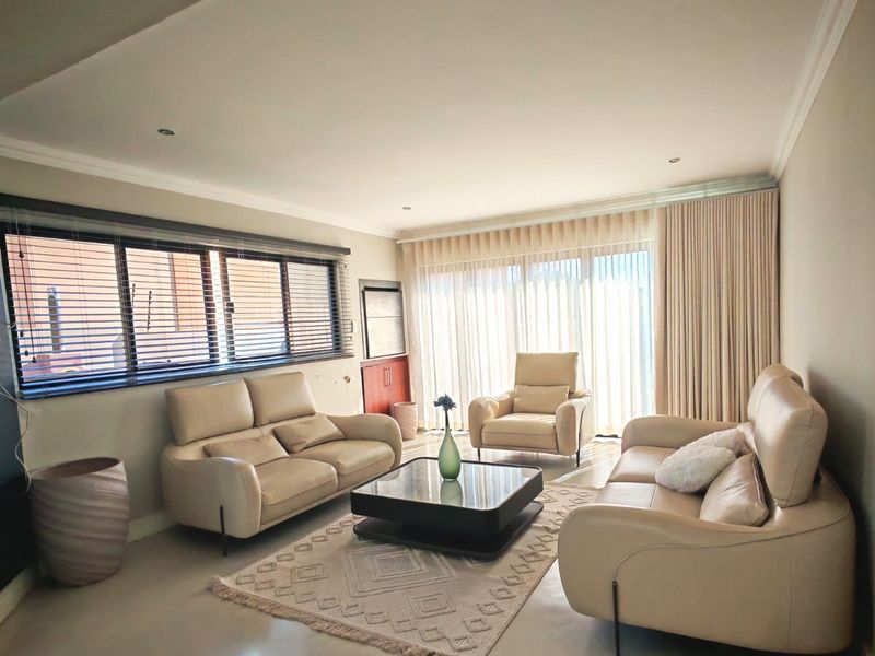 A well-maintained living room featuring polished concrete floors, recessed lighting, and large sliding glass doors that provide ample natural light.