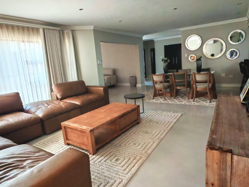 Spacious open-plan living and dining area featuring polished concrete floors, recessed lighting, and large windows with integrated curtain tracks.