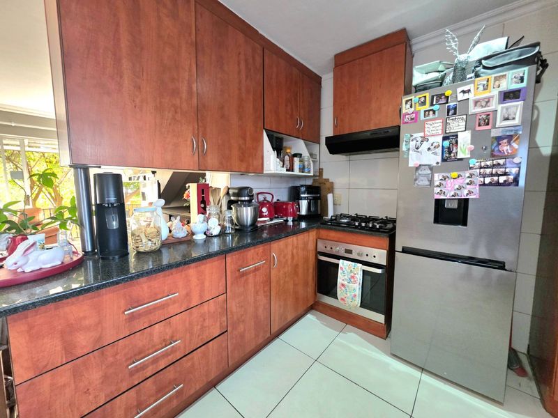 A functional kitchen featuring cherry wood cabinetry, granite countertops, a built-in oven, gas hob, and tiled flooring.