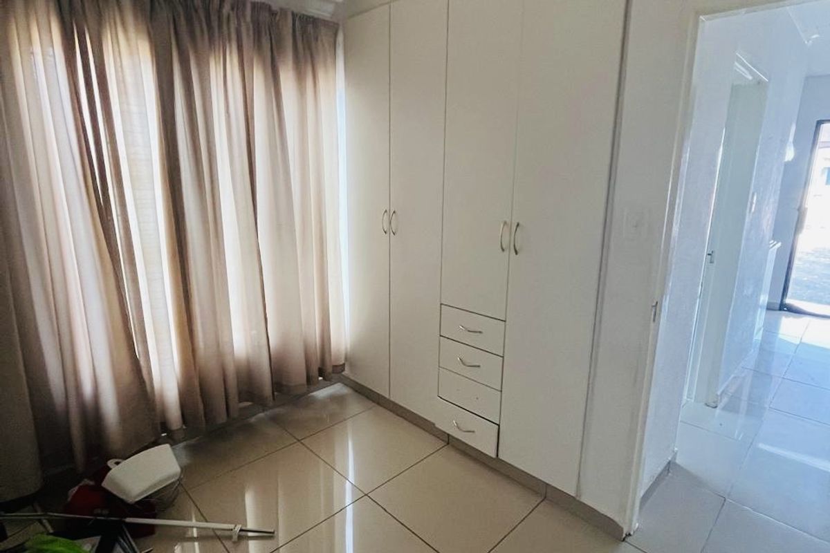 A bedroom featuring tiled flooring and built-in cupboards, offering a clean and functional space ready for personalization.