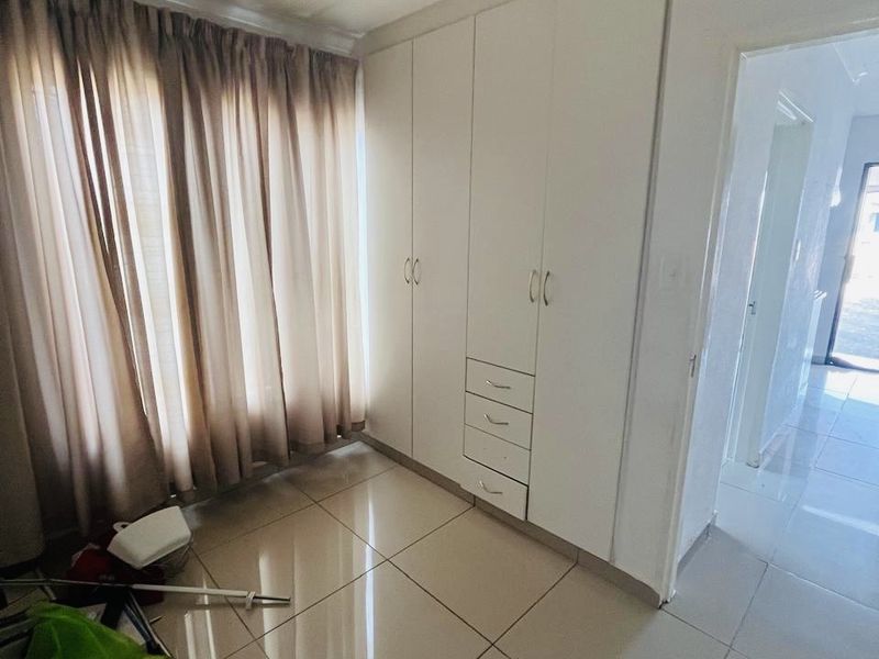 A bedroom featuring tiled flooring and built-in cupboards, offering a clean and functional space ready for personalization.