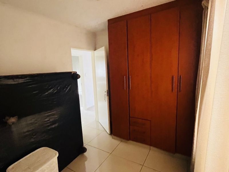 Bedroom featuring tiled flooring and a built-in wooden wardrobe, requiring minor cosmetic updates to improve the overall aesthetic.