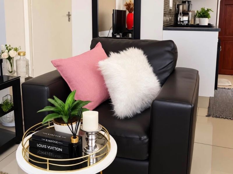 An open-plan living area featuring tiled flooring and a compact kitchen with a modern extractor fan and tiled backsplash.