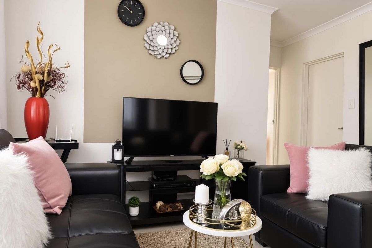 A well-maintained living room featuring a neutral accent wall, coving, and clean finishes, providing a comfortable and inviting space.