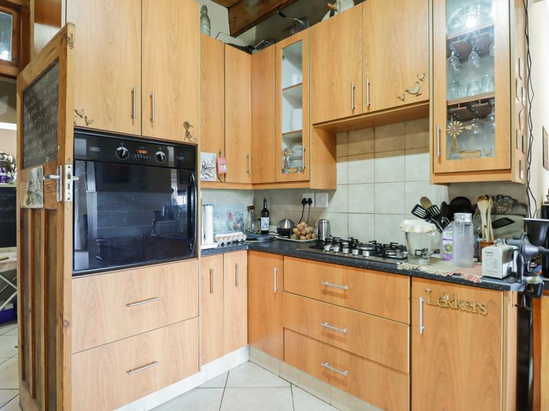 A functional kitchen featuring light wood-tone cabinetry, a built-in oven, gas hob, and tiled backsplash, offering a practical layout for daily cooking.