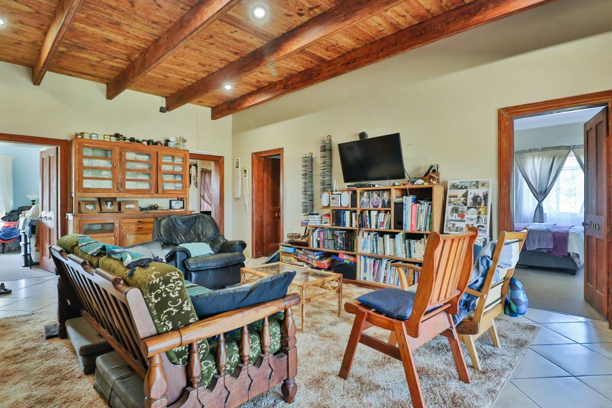 Spacious living room featuring exposed timber ceiling beams, recessed lighting, and tiled flooring, providing a warm and rustic atmosphere.