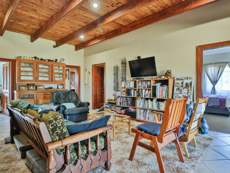 Spacious living room featuring exposed timber ceiling beams, recessed lighting, and tiled flooring, providing a warm and rustic atmosphere.