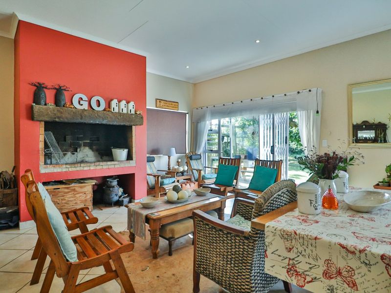 Spacious living room featuring a prominent built-in fireplace with a rustic timber mantel and direct access to the garden through sliding glass doors.