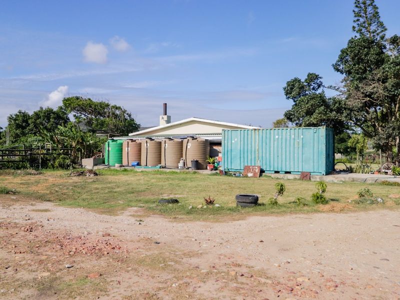Rear view of the farm property featuring multiple water storage tanks, a shipping container, and a chimney on the main structure.