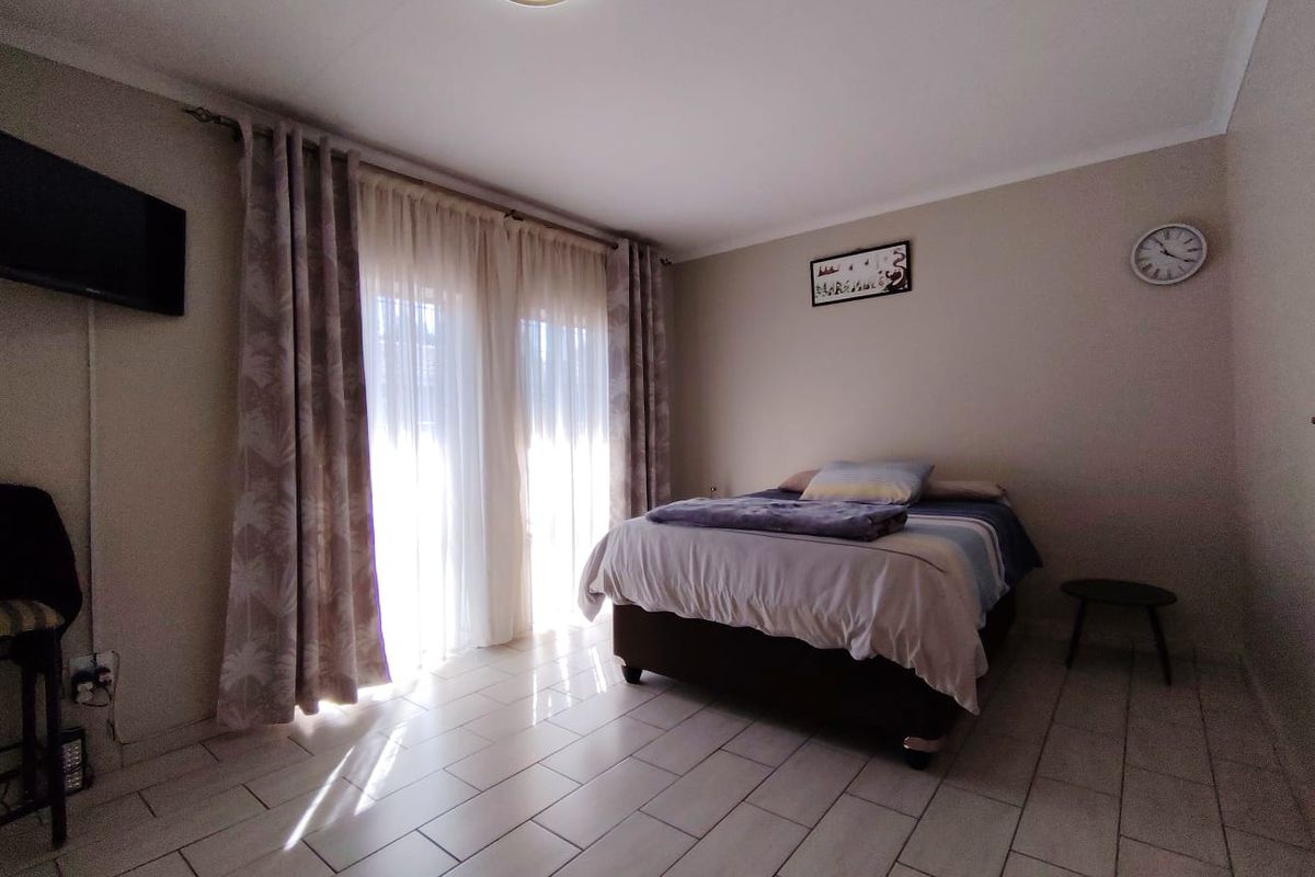 A bedroom featuring tiled flooring and a sliding glass door providing natural light.