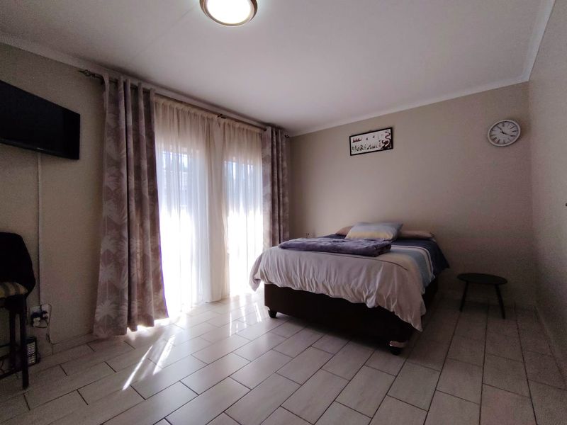 A bedroom featuring tiled flooring and a sliding glass door providing natural light.