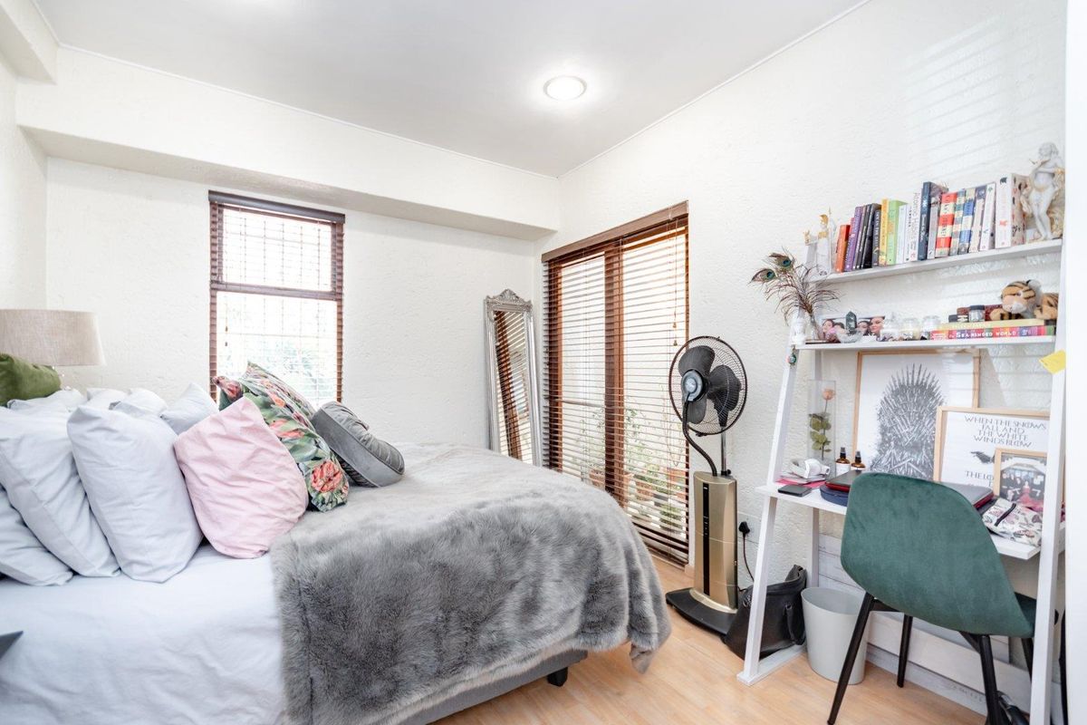 A well-lit bedroom featuring laminate flooring, recessed downlighting, and timber venetian blinds, offering a functional and comfortable living space.