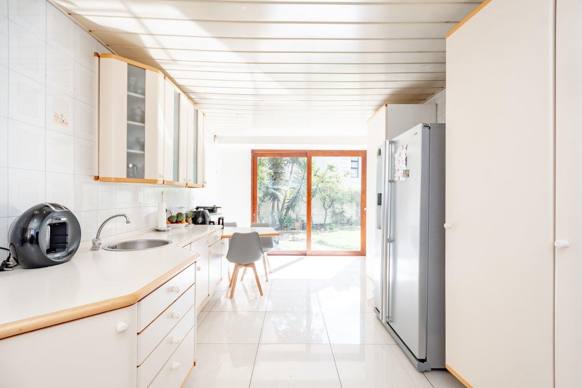 A functional kitchen featuring built-in cabinetry, tiled flooring, and a sliding glass door providing direct access to the garden area.