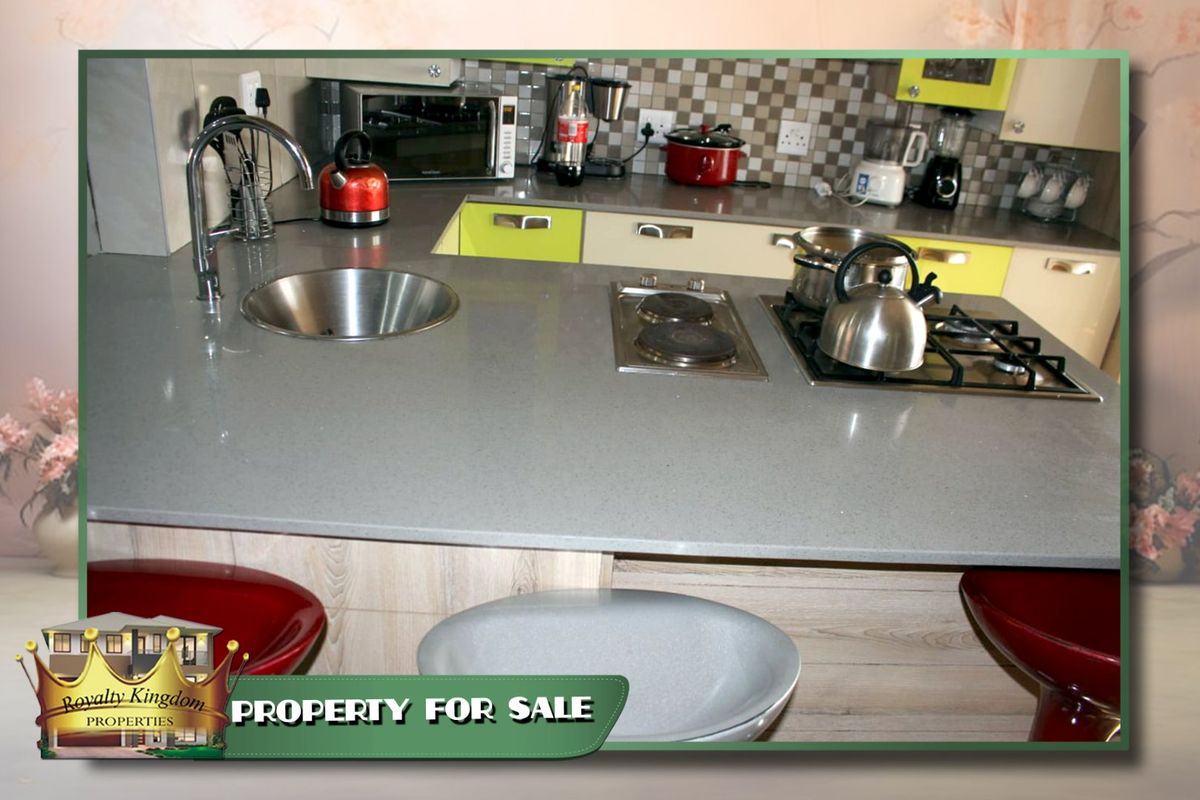 A kitchen featuring a stone countertop with an integrated hob, undermount sink, and tiled backsplash with fitted cabinetry.