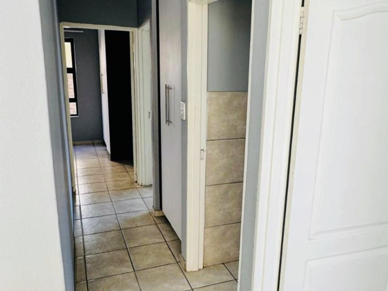 A functional hallway featuring tiled flooring, built-in storage cupboards, and access to multiple rooms within the apartment.