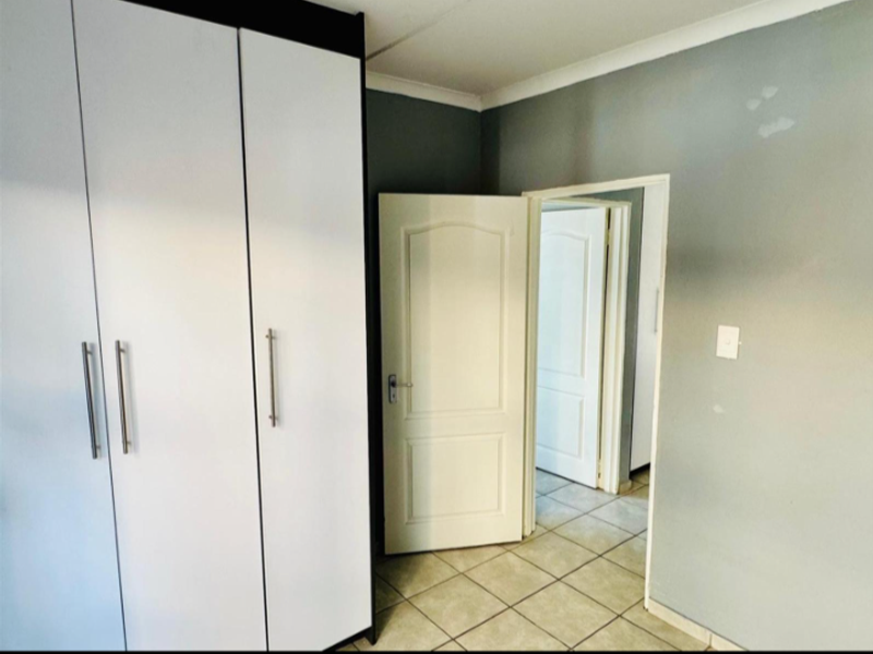 A bedroom featuring built-in cupboards, tiled flooring, and neutral wall finishes, offering a clean and functional space.