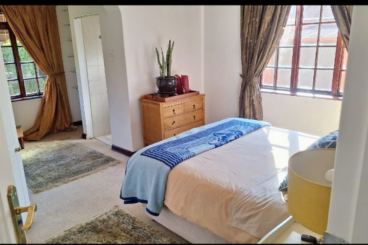 A bedroom featuring timber-framed windows, carpeted flooring, and an archway leading to an adjoining space.