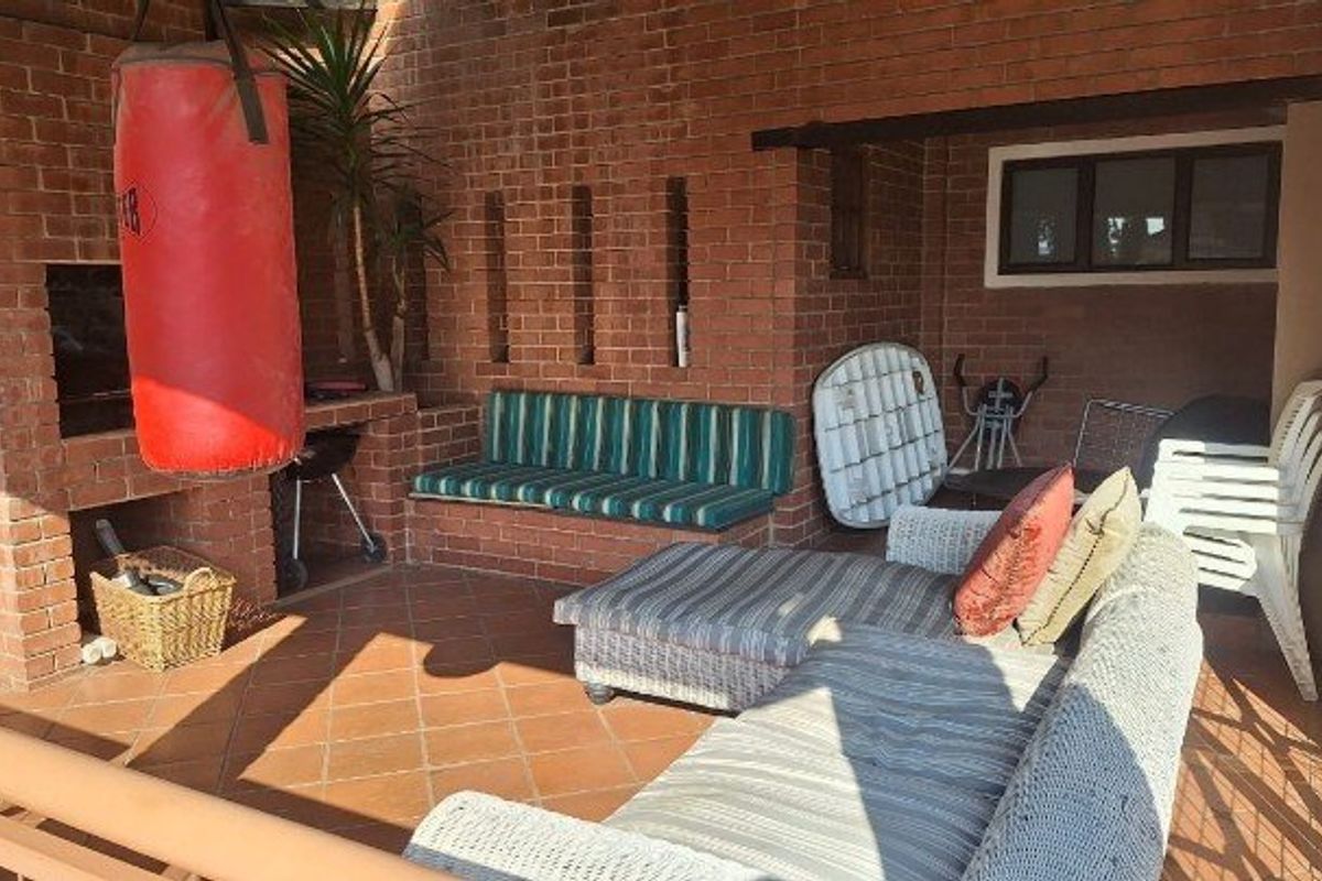 Covered patio area featuring a built-in brick braai and integrated brick seating, providing a functional outdoor entertainment space.