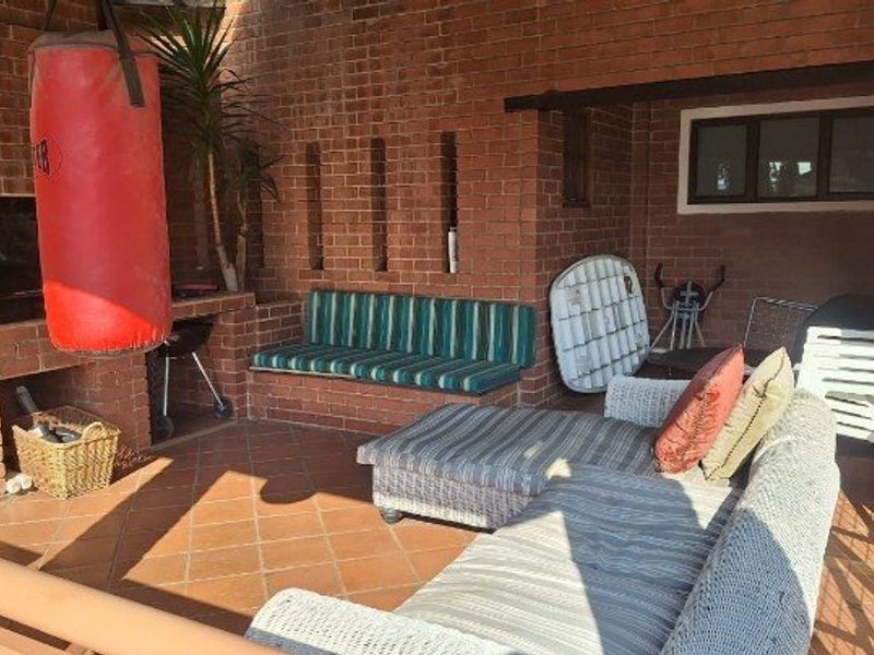 Covered patio area featuring a built-in brick braai and integrated brick seating, providing a functional outdoor entertainment space.
