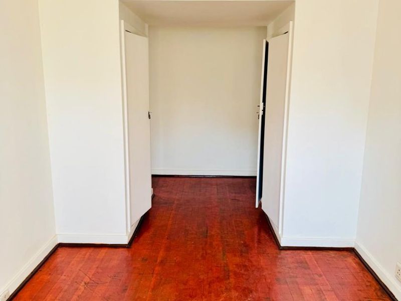 An empty bedroom featuring original hardwood flooring and a built-in cupboard, offering a blank canvas for renovation.