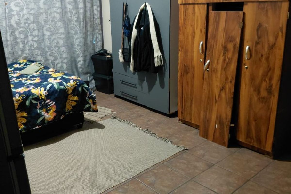 A bedroom featuring tiled flooring and built-in storage space, currently showing signs of wear and maintenance requirements.
