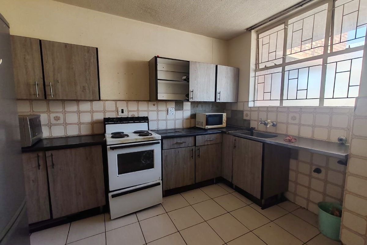 A functional kitchen featuring laminate cabinetry, tiled backsplash, and tiled flooring, requiring cosmetic updates to improve its overall condition and aesthetic appeal.