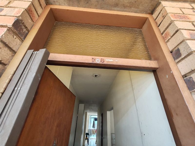 View of the apartment entrance featuring a brick facade and a timber door frame with a transom window above the doorway.