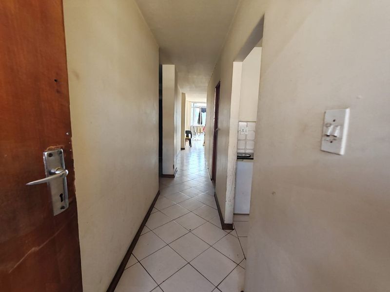 A functional apartment hallway featuring tiled flooring and neutral wall finishes, providing access to adjacent living areas.