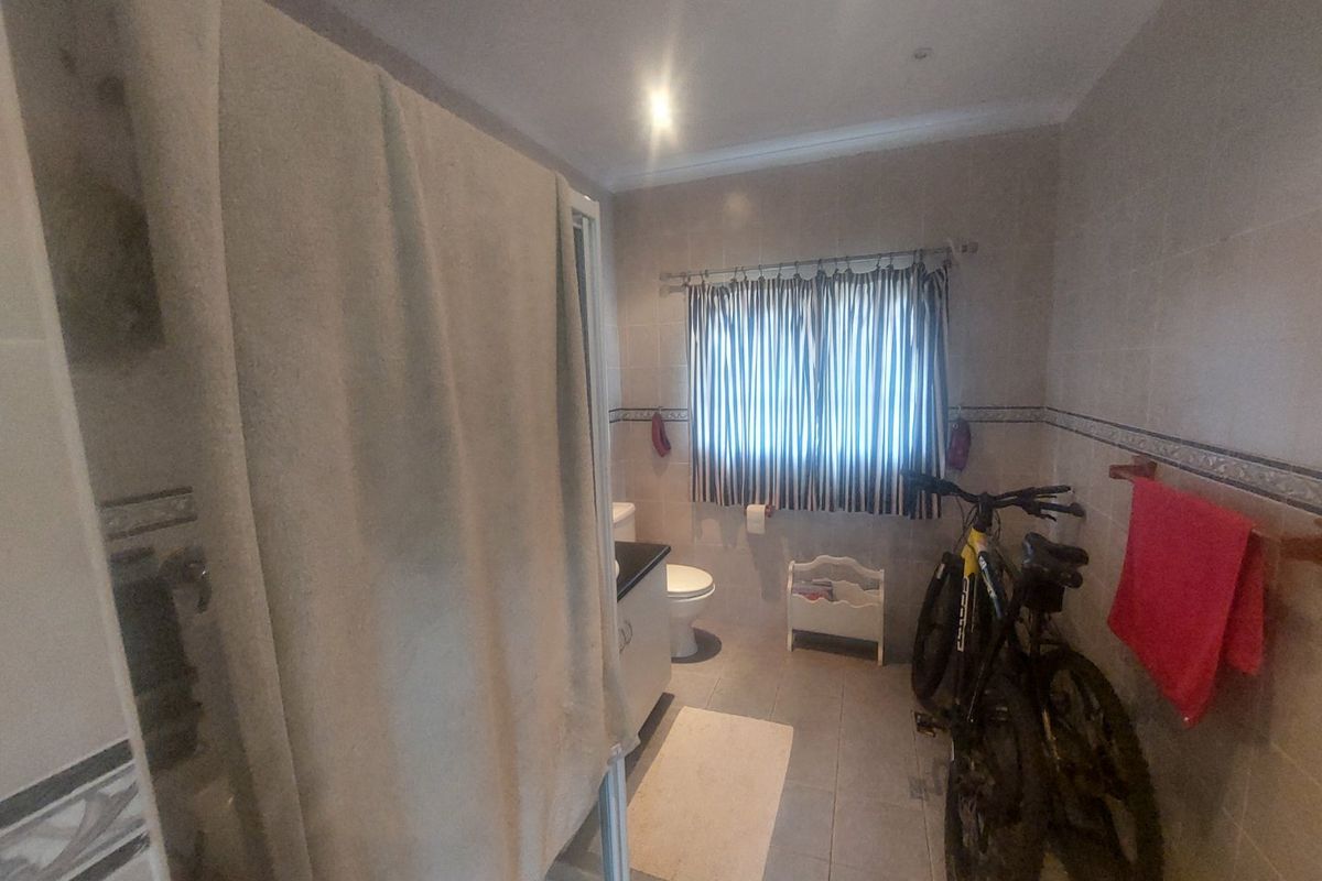 A functional bathroom featuring tiled walls and flooring, a shower enclosure, and a vanity cabinet, providing a practical layout for daily use.