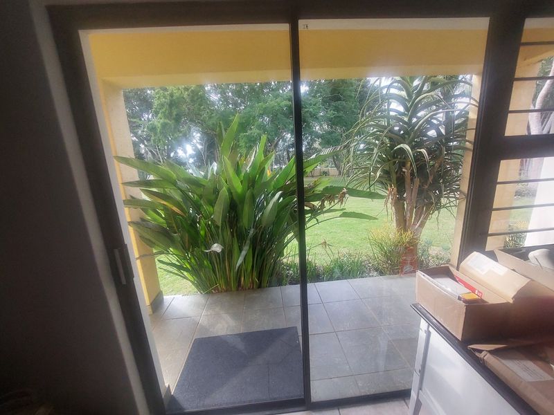 A covered patio area featuring tiled flooring and a sliding glass door, providing direct access to a private garden space.