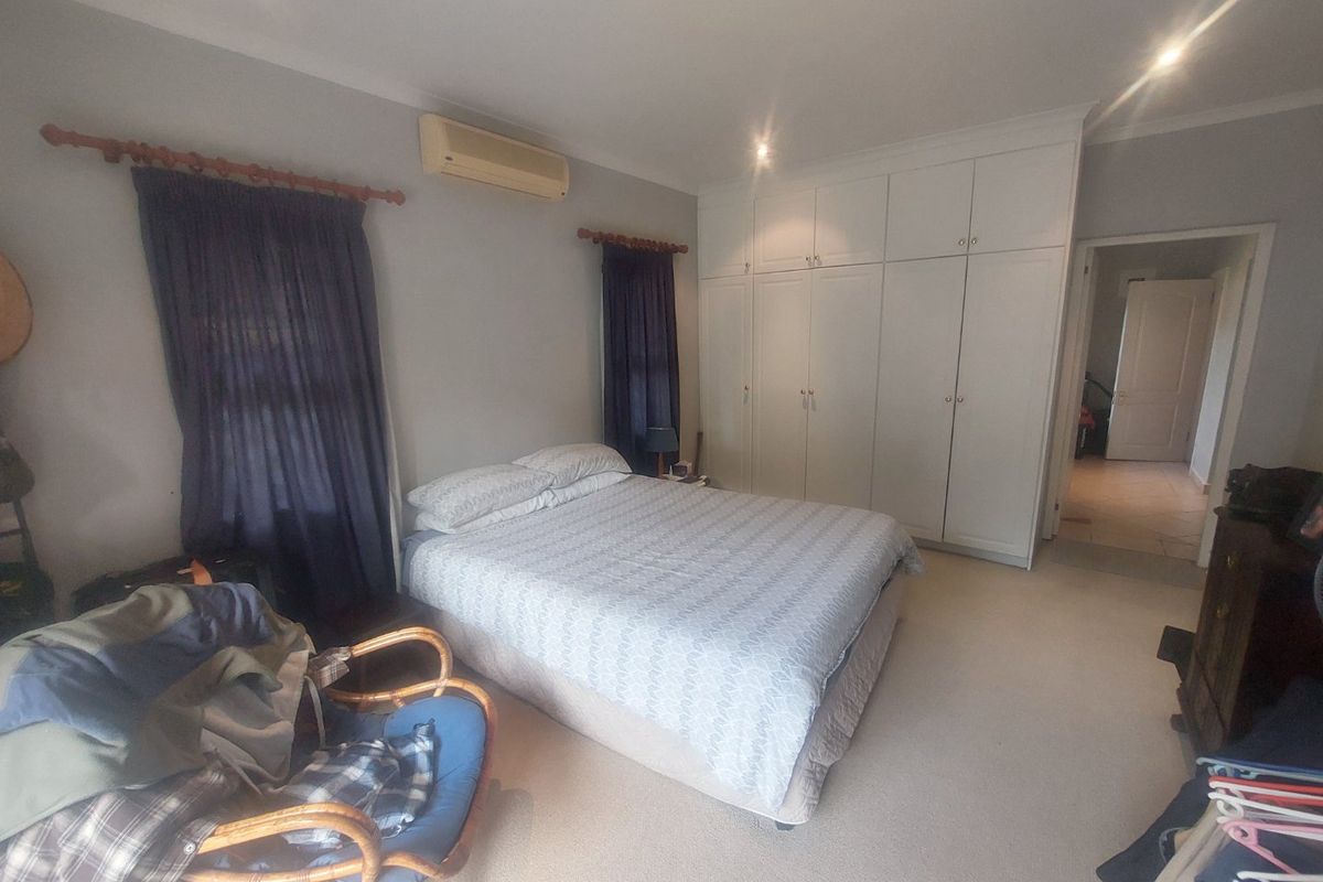 Spacious bedroom featuring extensive built-in cabinetry, carpeted flooring, and a wall-mounted air conditioning unit.