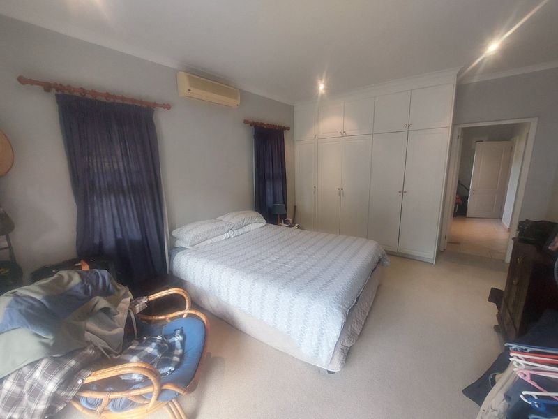 Spacious bedroom featuring extensive built-in cabinetry, carpeted flooring, and a wall-mounted air conditioning unit.