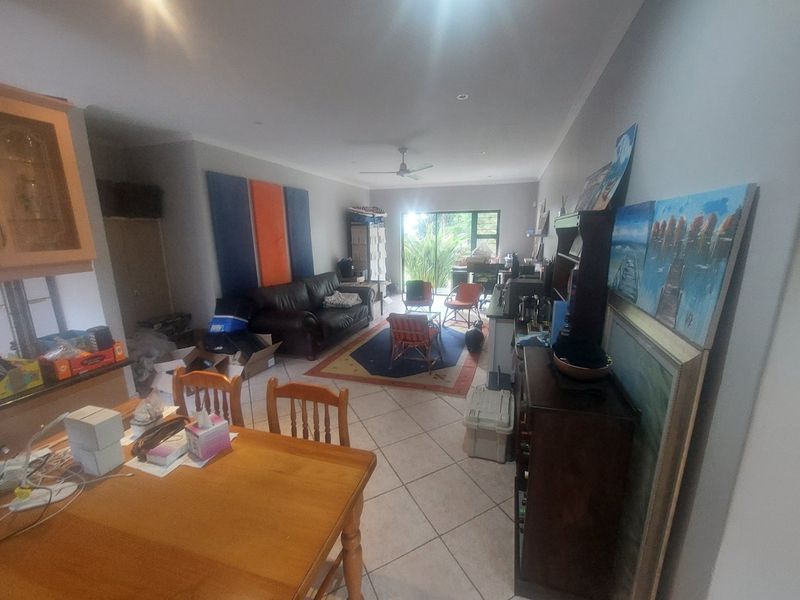 Spacious open-plan living and dining area featuring tiled flooring, recessed lighting, a ceiling fan, and large sliding glass doors leading to the outdoors.